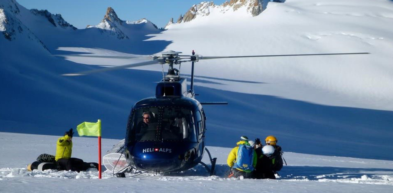 Group of skiers waiting for heli to fly off in mountains