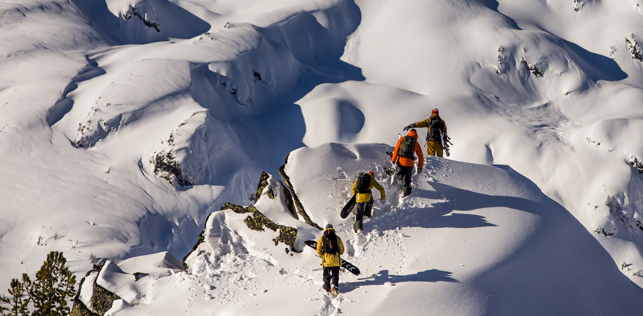 Group of snowboarders walking up a mountain