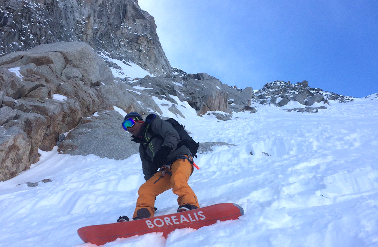 Romain Guide on snowboard in steep couloir